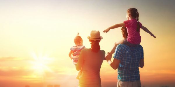 happy family at sunset. father, mother and two children daughters having fun and playing in nature. the child sits on the shoulders of his father.